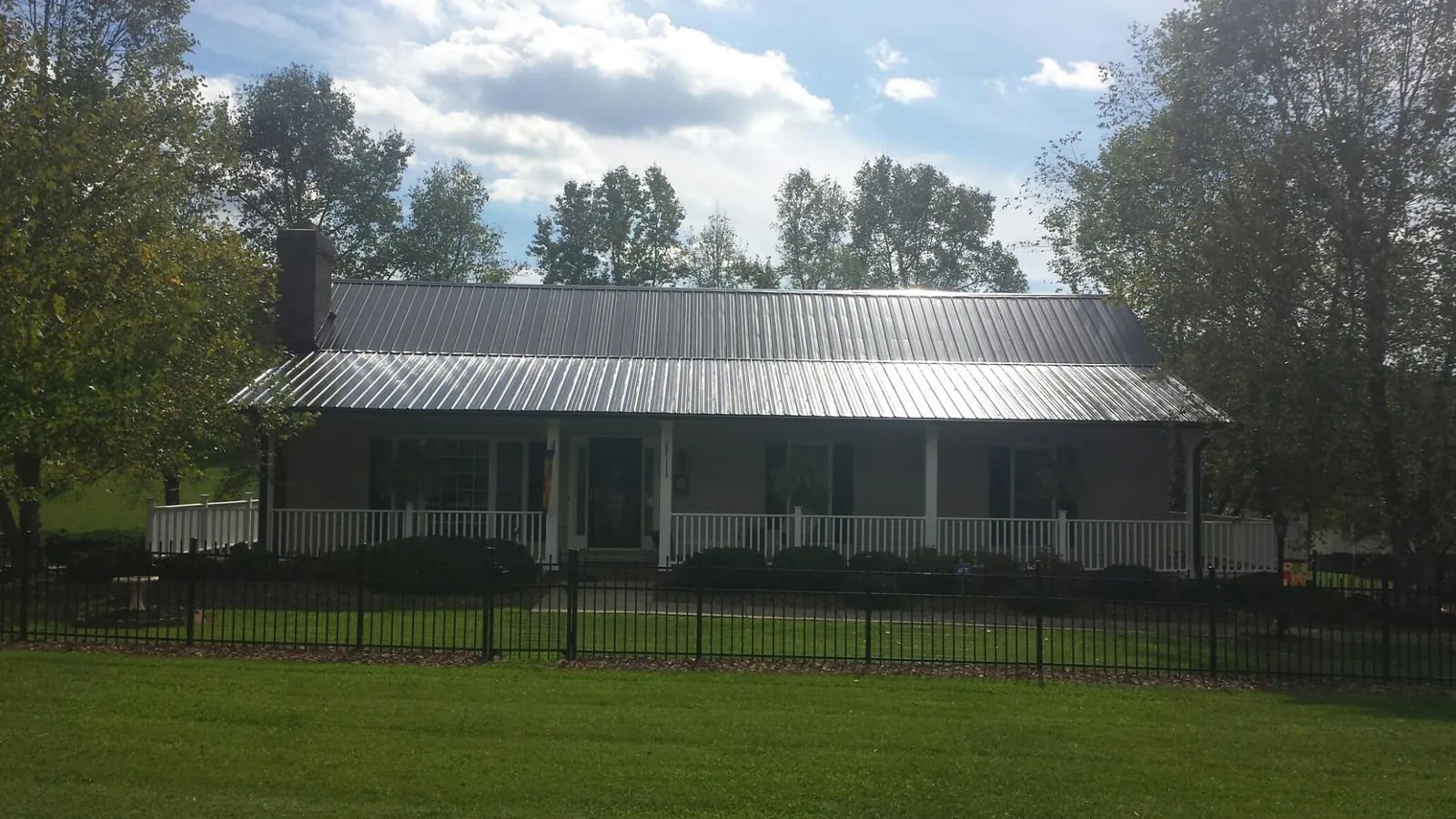 Gray metal roof on a brick ranch with a full width front porch — Gutter Guard Installation work by our crew in Kingston